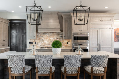 Eat-in kitchen - southwestern l-shaped medium tone wood floor and brown floor eat-in kitchen idea in St Louis with shaker cabinets, beige cabinets, quartzite countertops, beige backsplash, subway tile backsplash, stainless steel appliances, an island and white countertops