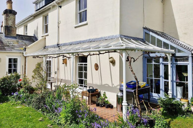 Medium sized traditional back veranda in Dorset with tiled flooring and an awning.