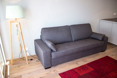 Idée de décoration pour un petit salon design ouvert avec un mur gris, parquet clair, aucune cheminée et un téléviseur indépendant.