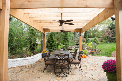 This is an example of a mid-sized traditional backyard patio in St Louis with natural stone pavers and a pergola.