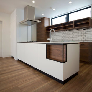 Foto de cocina lineal, moderna, pequeña, abierta, con fregadero bajoencimera, puertas de armario marrones, encimera de acrílico, salpicadero blanco, electrodomésticos de acero inoxidable, suelo de contrachapado, suelo marrón, encimeras blancas y papel pintado