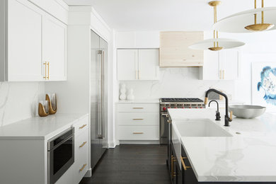 This is an example of a contemporary l-shaped kitchen in Philadelphia with a farmhouse sink, shaker cabinets, white cabinets, white splashback, stone slab splashback, stainless steel appliances, dark hardwood floors, with island, brown floor and white benchtop.
