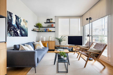 Diseño de salón abierto y gris y blanco contemporáneo de tamaño medio con paredes blancas, suelo de madera en tonos medios, televisor en una esquina y alfombra