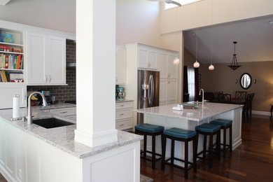 Inspiration for a large modern l-shaped dark wood floor open concept kitchen remodel in Denver with a single-bowl sink, shaker cabinets, white cabinets, quartz countertops, brown backsplash, glass tile backsplash, stainless steel appliances and an island