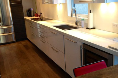 Eat-in kitchen - large contemporary galley medium tone wood floor eat-in kitchen idea in Calgary with an undermount sink, flat-panel cabinets, dark wood cabinets, quartz countertops, stainless steel appliances and a peninsula
