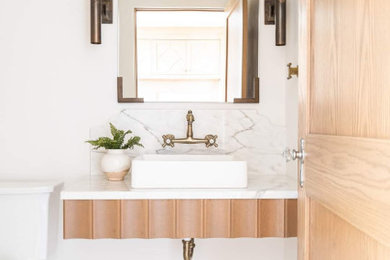 Example of a mid-sized cottage porcelain tile and white floor powder room design in Other with light wood cabinets, white walls, a vessel sink, marble countertops, white countertops and a floating vanity