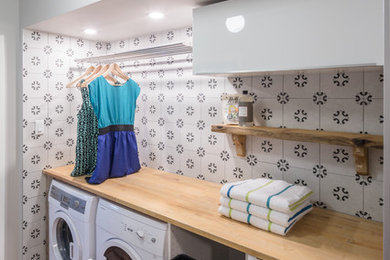 Inspiration for a small contemporary single-wall dedicated laundry room in Ottawa with flat-panel cabinets, white cabinets, wood benchtops, grey walls, light hardwood floors, a side-by-side washer and dryer and beige benchtop.