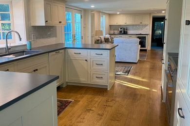 Inspiration for a mid-sized timeless u-shaped medium tone wood floor and brown floor open concept kitchen remodel in Boston with shaker cabinets, white cabinets, quartz countertops, white backsplash, ceramic backsplash, paneled appliances, a peninsula and gray countertops