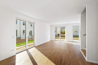Mittelgroßes, Offenes Modernes Wohnzimmer mit weißer Wandfarbe, Laminat und braunem Boden in Berlin