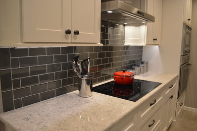 Example of a large brown floor kitchen design in Other with shaker cabinets, white cabinets, black backsplash, subway tile backsplash and stainless steel appliances