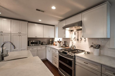 This is an example of a mid-sized beach style galley open plan kitchen in Philadelphia with an undermount sink, shaker cabinets, white cabinets, quartzite benchtops, white splashback, mosaic tile splashback, stainless steel appliances, dark hardwood floors, with island and brown floor.