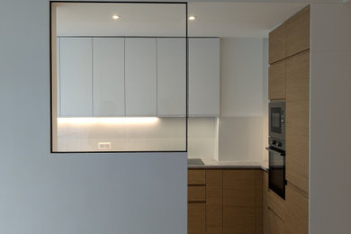 Idée de décoration pour une grande cuisine avec un évier encastré, un plan de travail en stratifié, une crédence blanche, une crédence en céramique, un électroménager noir, un sol en carrelage de céramique, un sol beige et un plan de travail gris.