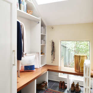 Idées déco pour une entrée éclectique de taille moyenne avec un vestiaire, un mur beige, un sol en carrelage de céramique, une porte simple, une porte blanche et un sol noir.