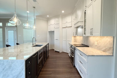 Inspiration for a huge l-shaped vinyl floor and brown floor kitchen pantry remodel in Dallas with a double-bowl sink, recessed-panel cabinets, beige cabinets, quartzite countertops, beige backsplash, stone slab backsplash, stainless steel appliances, an island and beige countertops