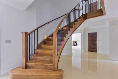 Foto de escalera curva actual grande con escalones de madera, contrahuellas de madera y barandilla de varios materiales