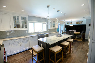 Inspiration for a large transitional u-shaped medium tone wood floor and brown floor eat-in kitchen remodel in DC Metro with an island, a farmhouse sink, recessed-panel cabinets, white cabinets, marble countertops, stainless steel appliances, gray backsplash and porcelain backsplash