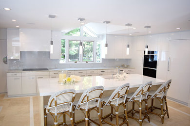 Example of a large trendy l-shaped laminate floor eat-in kitchen design in Cleveland with an undermount sink, flat-panel cabinets, light wood cabinets, marble countertops, gray backsplash, stone slab backsplash, black appliances and an island