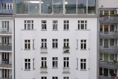 Example of a trendy white three-story apartment exterior design in Berlin