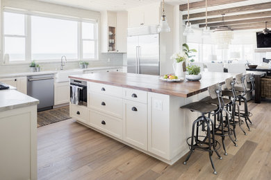 Example of a mid-sized beach style u-shaped eat-in kitchen design in Los Angeles with shaker cabinets, white cabinets, solid surface countertops and an island