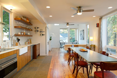 Open concept kitchen - mid-sized scandinavian single-wall light wood floor open concept kitchen idea in Raleigh with a farmhouse sink, flat-panel cabinets, light wood cabinets, solid surface countertops, stainless steel appliances and no island