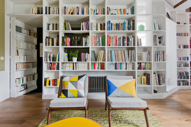 Mid-sized scandinavian enclosed living room in Paris with a library, white walls, light hardwood floors, no fireplace and no tv.