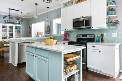 Photo of a mid-sized beach style u-shaped eat-in kitchen in Charleston with shaker cabinets, recycled glass benchtops, blue splashback, ceramic splashback, stainless steel appliances, with island, a single-bowl sink, white cabinets, dark hardwood floors and brown floor.