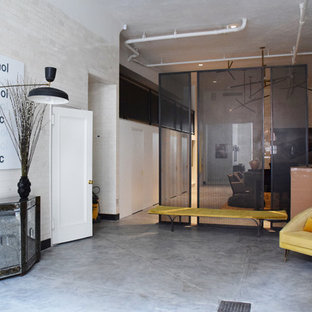 Photo of a large eclectic foyer in New York with white walls and concrete floors.