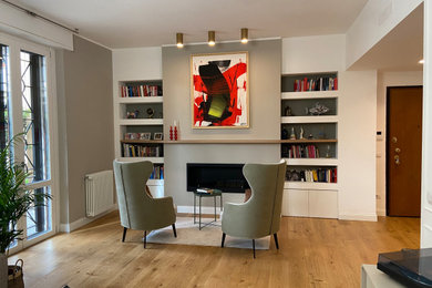Ispirazione per un soggiorno minimal aperto con libreria, pareti beige, parquet chiaro e camino lineare Ribbon