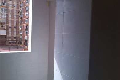 Modelo de cuarto de baño minimalista pequeño con ducha esquinera, sanitario de dos piezas, baldosas y/o azulejos grises, baldosas y/o azulejos de cerámica, paredes grises, suelo de madera clara, aseo y ducha y lavabo integrado