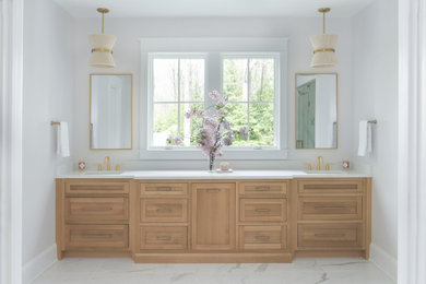ワシントンD.C.にある広いトラディショナルスタイルのおしゃれなマスターバスルーム (淡色木目調キャビネット、白い洗面カウンター、洗面台2つ、造り付け洗面台) の写真