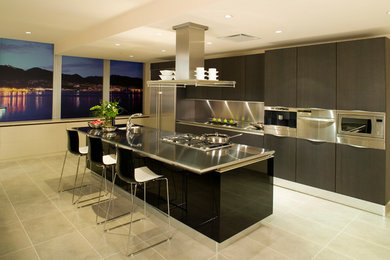 Inspiration for a mid-sized modern single-wall porcelain tile and beige floor kitchen remodel in Philadelphia with a drop-in sink, flat-panel cabinets, stainless steel countertops, gray backsplash, stainless steel appliances, an island, metal backsplash and dark wood cabinets
