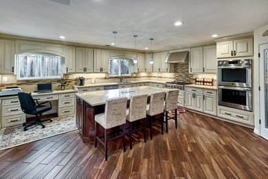 Inspiration for a huge timeless u-shaped dark wood floor and brown floor enclosed kitchen remodel in San Francisco with an undermount sink, raised-panel cabinets, beige cabinets, quartz countertops, beige backsplash, stainless steel appliances, an island and gray countertops
