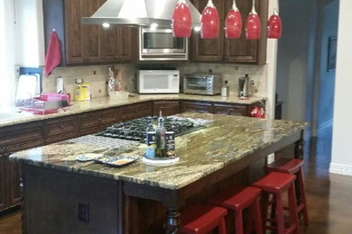 Inspiration for a large timeless l-shaped concrete floor eat-in kitchen remodel in Austin with a drop-in sink, dark wood cabinets, granite countertops, multicolored backsplash, ceramic backsplash, stainless steel appliances and an island