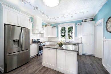 Inspiration for a mid-sized transitional l-shaped vinyl floor and gray floor eat-in kitchen remodel in Salt Lake City with a farmhouse sink, raised-panel cabinets, white cabinets, granite countertops, white backsplash, ceramic backsplash, stainless steel appliances, an island and gray countertops