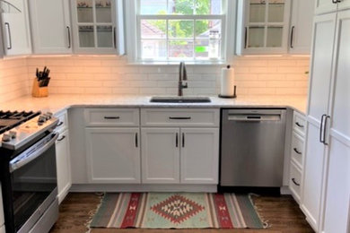 Inspiration for a large transitional u-shaped medium tone wood floor and brown floor eat-in kitchen remodel in Detroit with an undermount sink, recessed-panel cabinets, white cabinets, quartz countertops, white backsplash, ceramic backsplash, stainless steel appliances, an island and gray countertops