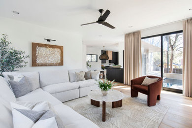 Diseño de salón abierto minimalista de tamaño medio con paredes blancas, suelo de madera clara, televisor colgado en la pared y suelo beige