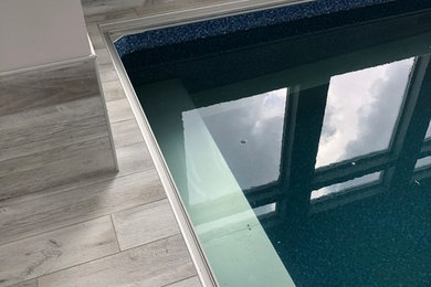 Design ideas for a contemporary indoor rectangular infinity pool in Salt Lake City with a pool house and tile.