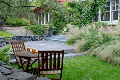 Inspiration for a mid-sized contemporary backyard patio in Montreal with natural stone pavers and a pergola.
