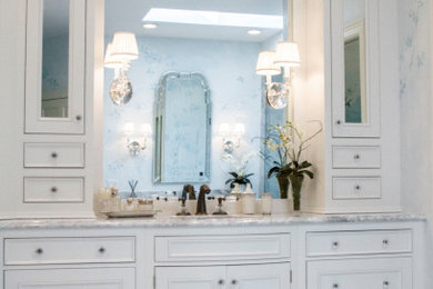 Inspiration for a large timeless master white tile and marble tile marble floor, white floor, double-sink and wallpaper bathroom remodel in St Louis with furniture-like cabinets, white cabinets, a one-piece toilet, blue walls, an undermount sink, marble countertops, a hinged shower door, white countertops and a built-in vanity