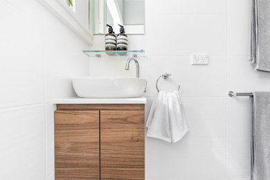 Small traditional 3/4 bathroom in Sydney with flat-panel cabinets, medium wood cabinets, a corner shower, a two-piece toilet, white tile, white walls, a vessel sink, multi-coloured floor, a hinged shower door, white benchtops, a single vanity and a floating vanity.