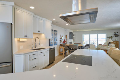 Kitchen - mid-sized l-shaped vinyl floor and beige floor kitchen idea in Other with an undermount sink, flat-panel cabinets, white cabinets, stainless steel appliances, an island, white countertops and white backsplash