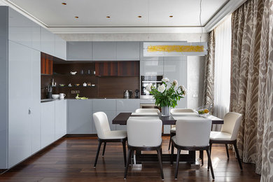 Contemporary l-shaped open plan kitchen in London with flat-panel cabinets, grey cabinets, brown splashback, stainless steel appliances, dark hardwood floors and no island.