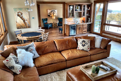 Inspiration for a large rustic loft-style dark wood floor and brown floor game room remodel in Other with beige walls, a corner fireplace, a stone fireplace and a media wall