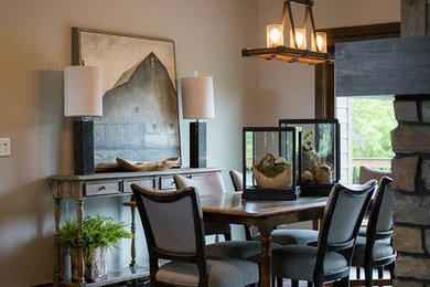 Example of a mid-sized farmhouse dark wood floor and brown floor enclosed dining room design in Other with beige walls, a standard fireplace and a stone fireplace