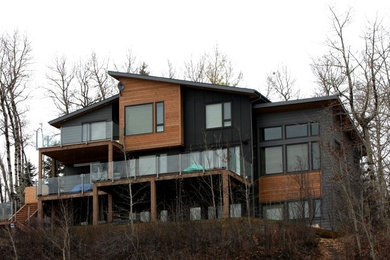 Inspiration for a large contemporary three-storey black house exterior in Calgary with mixed siding and a shed roof.