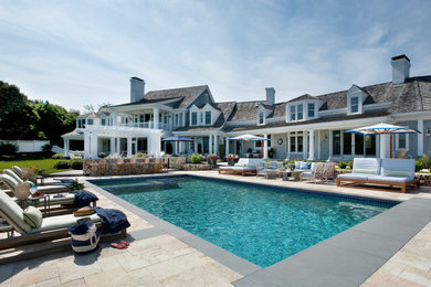 This is an example of a large beach style backyard rectangular lap pool in Boston with a hot tub and tile.