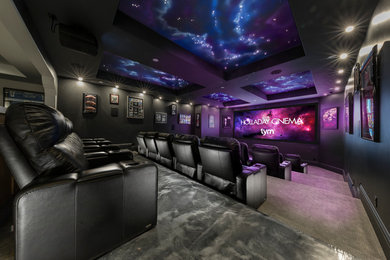 Photo of a large transitional open concept home theatre in Salt Lake City with grey walls, carpet, a projector screen and beige floor.