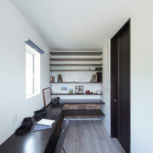 他の地域のモダンスタイルのおしゃれなホームオフィス・仕事部屋 (白い壁、造り付け机、グレーの床) の写真