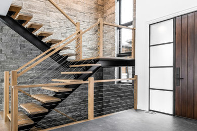 Foto de escalera contemporánea sin contrahuella con escalones de madera y barandilla de cable