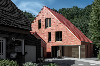 Inspiration for a large contemporary three-storey brick red house exterior in Other with a tile roof, a red roof and a gable roof.